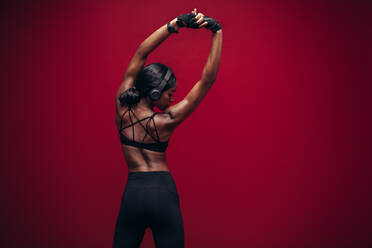 Fit woman doing exercise against red background. African female