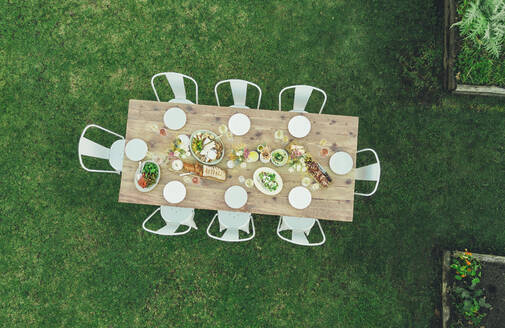 Luftaufnahme eines gedeckten Tisches im Freien in einem Gartenrestaurant mit leeren Stühlen, Tisch für eine Mahlzeit im Freien. - JLPSF25936