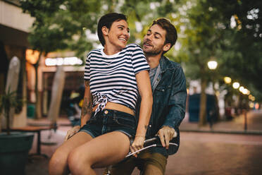 Smiling girl sitting on bicycle handlebar with her boyfriend. Beautiful couple enjoying on bicycle in the city. - JLPSF25937