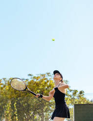 Eine Tennisspielerin, die gerade den Ball schlägt. Eine junge Sportlerin, die an einem Sommertag auf dem Platz Tennis spielt. - JLPSF25953