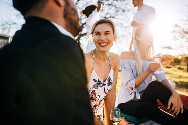 Group of cheerful young people talking to each other in party outdoors. Woman smiling with friends at garden . - JLPSF25982