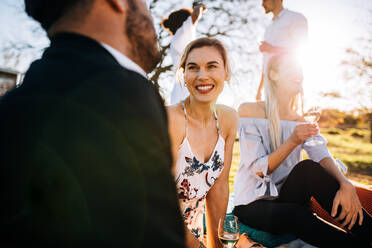Gruppe fröhlicher junger Leute, die sich auf einer Party im Freien unterhalten. Frau lächelt mit Freunden im Garten. - JLPSF25982