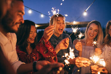 Junge Männer und Frauen genießen mit Feuerwerk. Gruppe von Freunden mit Wunderkerzen genießen Outdoor-Party. - JLPSF26002