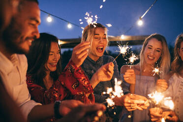 Young men and women enjoying with fireworks. Group of friends with sparklers enjoying outdoor party. - JLPSF26002