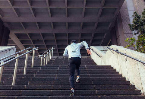 Mann, der die Treppe eines Gebäudes hinaufläuft; Sportler, der im Rahmen seines Trainings die Treppe hinaufsteigt. - JLPSF26011