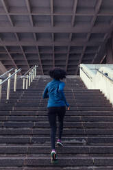 Frau, die die Treppe eines Gebäudes hinaufläuft. Sportlerin, die im Rahmen ihres körperlichen Trainings Treppen steigt. - JLPSF26012