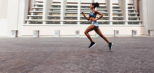 Frau, die am Morgen im Freien läuft. Frau in Laufkleidung sprintet auf der Straße. - JLPSF26021