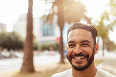 Smiling young man outdoors. Close up of a man with a broad smile looking away. - JLPSF26029