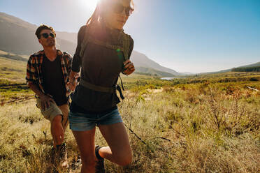 Junge Frau mit ihrem Freund auf einem Spaziergang durch die Landschaft. Junges Paar wandert gemeinsam durch extremes Gelände. - JLPSF26108