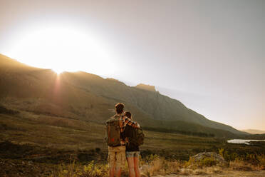 Rückansicht eines jungen Mannes und einer Frau auf Wanderschaft, die zusammen stehen und die Aussicht betrachten. Verliebtes Paar auf Wanderweg in Naturschutzgebiet. - JLPSF26114