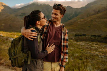 Aufnahme eines jungen Mannes und einer Frau auf einem Spaziergang auf dem Lande. Romantisches Wanderpärchen mit Rucksack, das sich ansieht. - JLPSF26117
