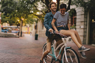 Young man and woman riding on a bicycle in the city. Happy couple on a bicycle in the city. - JLPSF26135