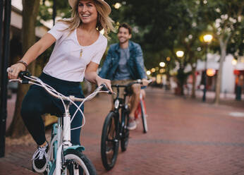 Frau radelt mit Freunden auf einer Straße in der Stadt. Freunde genießen eine Fahrradtour im Freien. - JLPSF26151