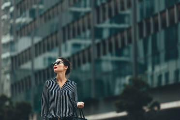 Young businesswoman walking outdoors. Asian female walking on the city street and looking away. - JLPSF26198