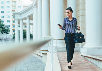 Außenaufnahme einer jungen Frau, die ein Mobiltelefon in der Stadt benutzt. Eine Geschäftsfrau benutzt ein Smartphone in der Stadt. - JLPSF26223