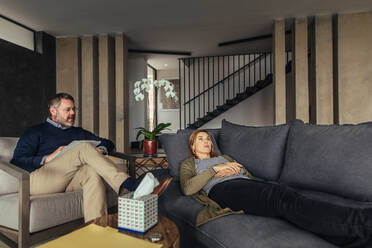 Depressed woman lying on sofa during psychotherapy session. Psychologist talking with female patient during therapy. - JLPSF26259