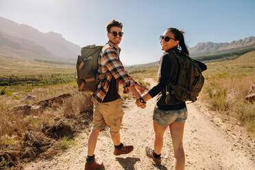 Rear view of happy young man and woman walking on hiking trail