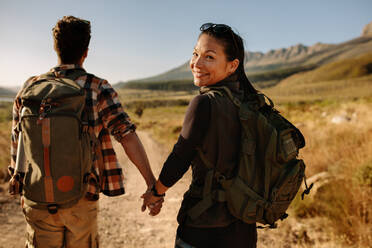 Junge Frau mit ihrem Freund auf einem Spaziergang durch die Landschaft. Glückliches junges Paar beim gemeinsamen Wandern an einem Sommertag. - JLPSF26291