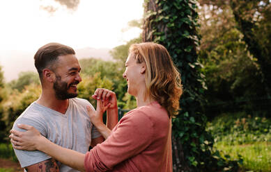 Lächelnder Mann mit seiner Freundin in einem Garten. Romantisches Paar verbringt Zeit miteinander in einem Park. - JLPSF26311