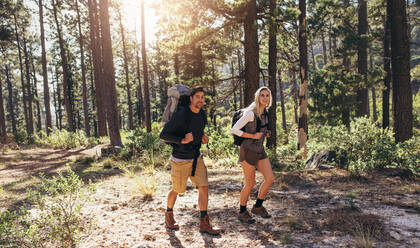 Ein Mann und eine Frau wandern auf einem Waldweg, ein Wandererpaar erkundet die Natur und geht durch den Wald. - JLPSF26324