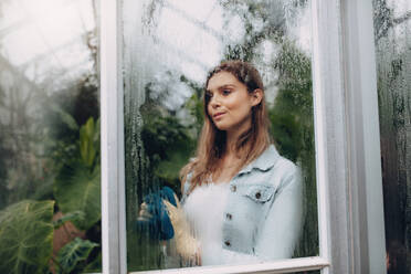 Caucasian female standing inside greenhouse. Woman gardener in plant nursery. - JLPSF26333