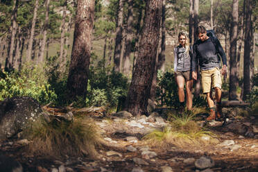 Mann und Frau wandern auf einem felsigen Pfad im Wald. Wandererpaar erkundet die Natur bei einem Spaziergang durch den Wald. - JLPSF26357