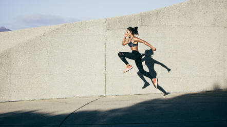 Sportliche Frau, die im Freien läuft und springt. Muskulöse Frau, die am Morgen trainiert. - JLPSF26388