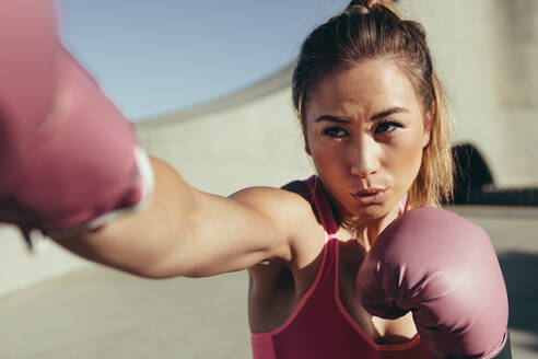 Fitte junge Frau mit Boxhandschuhen beim Schlagtraining. Weibliche Boxerin beim Boxen. - JLPSF26411