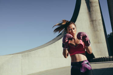 Junge muskulöse Frau beim Boxen. Weiblicher Boxer beim Boxtraining im Freien am Morgen. - JLPSF26413