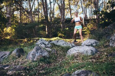 Morgenläuferin beim Joggen in einem Park. Frau läuft durch Felsen und Bäume in einem Park. - JLPSF26447