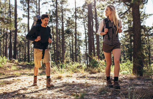 Ein Mann und eine Frau wandern auf einem Waldweg, ein Wandererpaar erkundet die Natur und geht durch den Wald. - JLPSF26474
