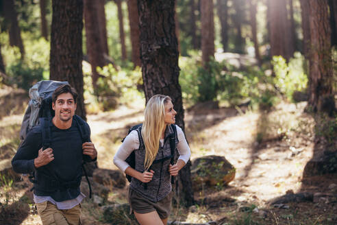 Mann und Frau wandern im Wald. Wandererpaar erkundet die Natur bei einem Spaziergang durch den Wald. - JLPSF26484