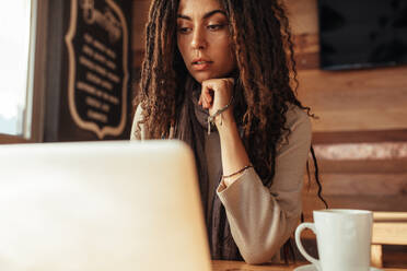 Nahaufnahme einer Frau, die an einem Restauranttisch sitzt und an einem Laptop arbeitet. Freiberufler, der in einem Café mit einem Kaffee sitzt und an einem Laptop arbeitet. - JLPSF26643