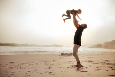 Glücklicher Vater und sein Sohn haben Spaß am Strand während der Sommerferien. Mann wirft seinen Sohn in die Luft am Strand. - JLPSF26731