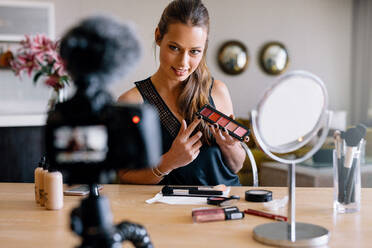 Junge Frau zeigt eine Make-up-Palette, während sie ihr Video aufnimmt. Frau macht ein Video für ihren Blog über Kosmetik. - JLPSF26759