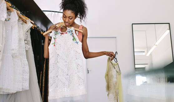 Modedesignerin, die sich in ihrem Atelier Designerkleider ansieht. Kundin, die in einem Modegeschäft Kleider auswählt. - JLPSF26782