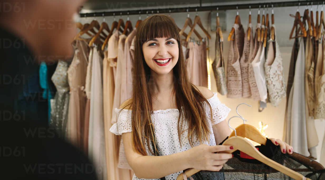 Happy customer selecting dresses in a fashion boutique. Assortment