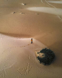Luftaufnahme einer Person, die zwischen den Dünen in der Wüste im Naturpark Corralejo, Fuerteventura, Kanarische Inseln, Spanien, spazieren geht. - AAEF16576