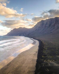 Aerial view of the wild coastline at sunrise along the coast in Caleta de Famara, a famous surf destination in Lanzarote, Canary Islands, Spain. - AAEF16578