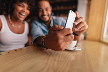 Junges Paar sitzt zusammen in einem Café und macht ein Selfie mit dem Mobiltelefon. - JLPSF26812