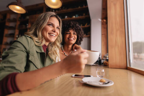 Zwei junge Frauen sitzen in einem Café und trinken Kaffee. Weibliche Freunde trinken Kaffee im Restaurant. - JLPSF26815