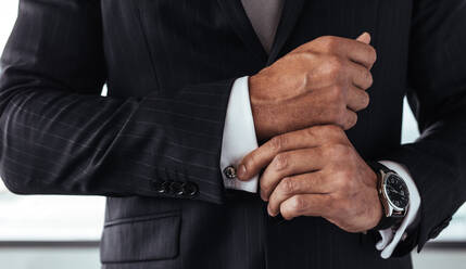 Nahaufnahme eines Geschäftsmannes in formellem Anzug, der einen Ärmel korrigiert. Männliche Hände, die die Manschetten eines weißen Hemdes fixieren. - JLPSF26895