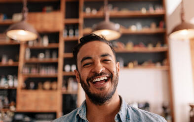 Close up portrait of happy young man laughing in a cafe. Young caucasian male in a coffee shop having fun. - JLPSF26921
