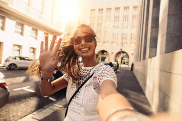 Tourist posiert für ein Selfie auf der Straße, Vloggerin nimmt Inhalte für ihren Reise-Vlog auf. - JLPSF26955