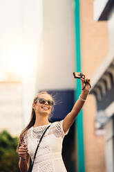 Young woman taking a selfie outdoors. Vlogger recording content for her travel vlog. - JLPSF26958