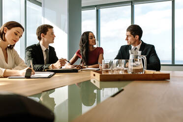 Eine Gruppe von Geschäftsleuten sitzt am Tisch und bespricht die neue Strategie ihres Unternehmens. von Geschäftsleuten, die sich im Konferenzraum treffen. - JLPSF26968