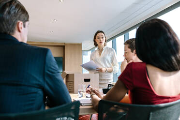 Geschäftsleute in einem modernen Konferenzraum, eine Frau steht und leitet eine Geschäftsbesprechung. - JLPSF26977