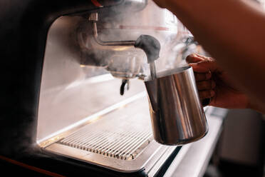 Close up image of a barista steaming milk on a coffee machine at cafe. Man making coffee by machine at cafe - JLPSF27012