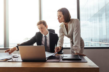 Business colleagues over viewing contract papers in office. Two business professionals working together on documents. - JLPSF27037