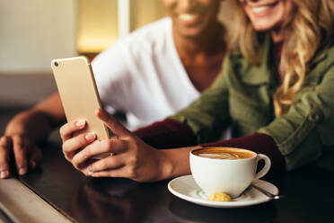 Nahaufnahme eines jungen Mannes und einer Frau, die zusammen in einem Café sitzen und ein Selfie mit dem Handy machen. Freunde machen ein Selfie in einem Café mit einem Smartphone. - JLPSF27050